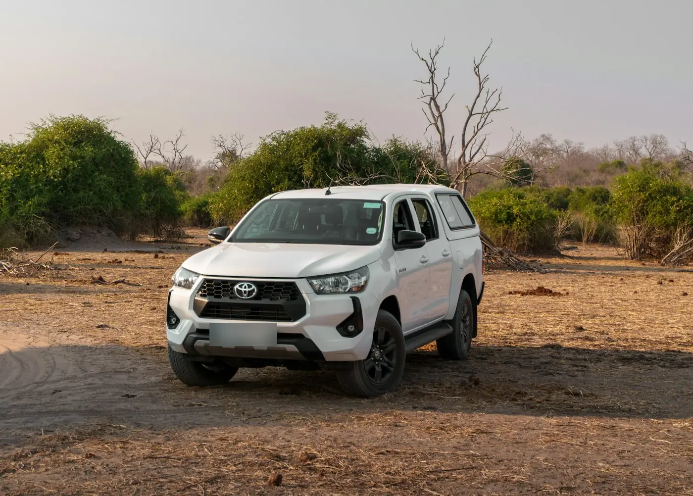 White Toyota Hilux double cab pickup on a dirt road